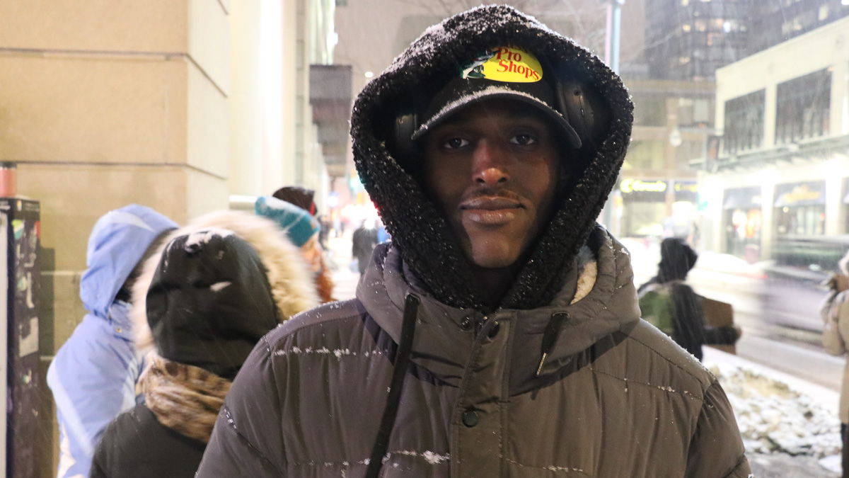 Idris Isse stands on the sidewalk as snow comes down around him at the Operation Come Home fundraiser