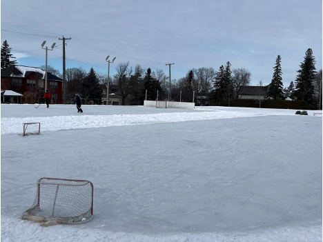 Photo of the two ice rinks in the Alta Vista community, with two skaters in the background playing hockey.