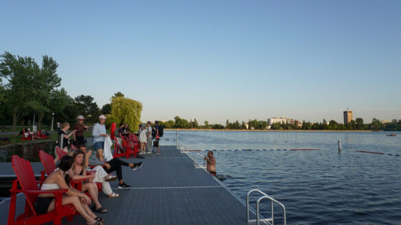 People sit on a dock in front of a roped-off swimming area in Dow's Lake.