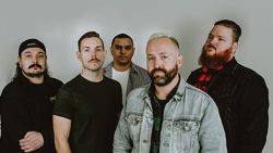 Colin Jacques, Jason Mooney, Steve Creaturo, Matthew Sears, Will Plummer, and Randy Frobel of pop-punk band We Were Sharks stand in front of a grey backdrop.