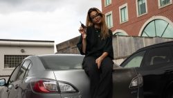 Girl sitting on top of her silver car