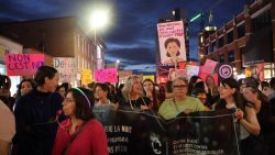 A group of people hold signs while walking downtown during the Take Back the Night march in Ottawa