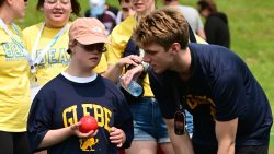 A girl, left, holds a red ball while a man, right, leans down and talks to her.