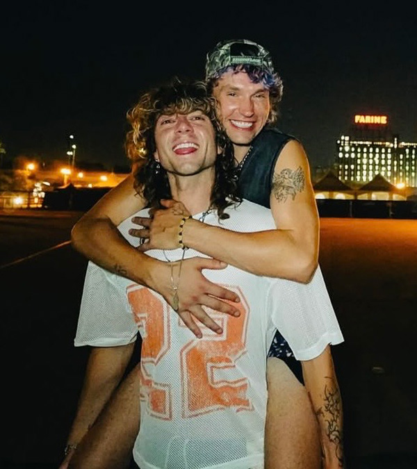 Jesse Lesniowski (AKA drag queen Saltina Shaker) piggybacks Eric Vance, the two of them smiling at the camera. Both of them are out of drag.