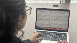 A women is seen comparing two Hansard documents, the one on the left is in English, the one on the right is in French.